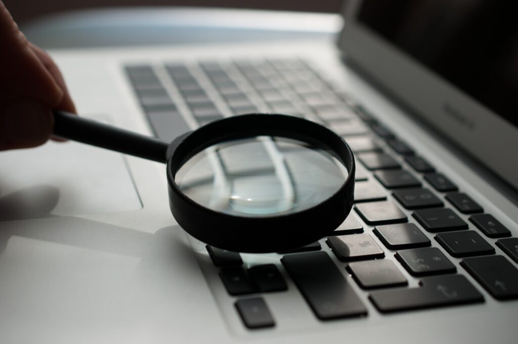 A magnifying glass over a laptop, representing how Google scrutinises a site's experience, expertise, authority and trust